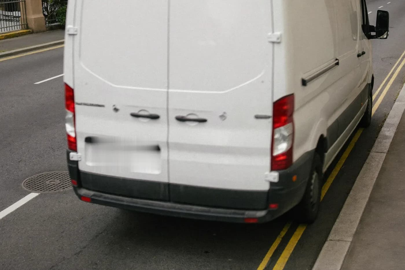 Weißer Transporter fährt mit leichter Bewegungsunschärfe von einer Stadtstraße an